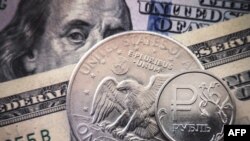 Uang logam rubel Rusia dengan latar lembarang uang dollar Amerika dalam foto ilustrasi di Moskow, 15 Maret 2022. (Foto: Alexander Nemenov/AFP)