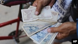 An ice cream street vendor shows his Cuban pesos in Havana on April 20, 2024. An increasing number of Cubans are having to grapple with the country's shortage of cash.
