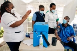 FILE - A nurse, left, prepares a shot of AstraZeneca COVID-19 vaccine, manufactured by the Serum Institute of India and provided through the global COVAX initiative, from a cold storage box in Machakos, Kenya, March 24, 2021.