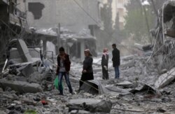 People walk through debris in the center of Afrin, Syria, March 24, 2018.