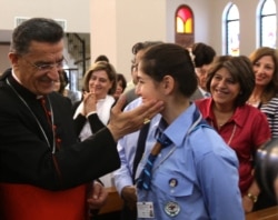 FILE - The Maronite Patriarch of Antioch and Cardinal of the Catholic Church, Bechara Boutros Al-Rai, left, blesses a girl scout at the Saint Charbel Maronite church in Amman, May 23, 2014.