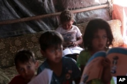 FILE - Syrian children read books in a refugee camp near Amman, Jordan, on June 5, 2023.