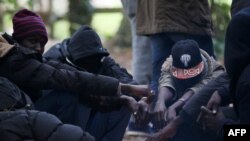 Des migrants soudanais attendent près d'un feu dans la forêt à Ouistreham, France, le 5 octobre 2017.