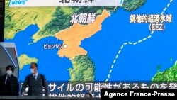 Pedestrians walk past a screen displaying a map after North Korea fired a missile into the sea off its east coast according to South Korea and Japan, during a news broadcast at Akihabara district in Tokyo, Jan. 5, 2022.