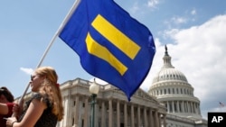 A supporter of LGBT rights holds up an "equality flag" on Capitol Hill in Washington, July 26, 2017, during an event held by Rep. Joe Kennedy, D-Mass., in support of transgender members of the military, in response to President Donald Trump's declaration that he wants transgender people barred from serving in the U.S. military "in any capacity," citing "tremendous medical costs and disruption."