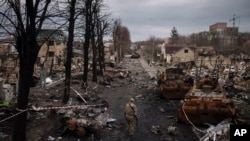 乌克兰军人走过布查镇被摧毁的俄军坦克残骸。(2022年4月6日)