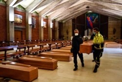 A coffin is carried in the San Giuseppe church in Seriate, one of the areas worst hit by coronavirus, near Bergamo, Italy, waiting to be taken to a crematory, March 26, 2020.