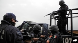 FILE - Seized weapons from alleged members of the Beltran Leyva drug cartel are taken away by federal agents after a news conference in Mexico City, June 26, 2009.