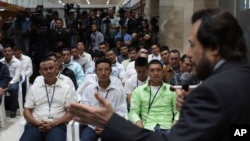 Un grupo de salvadoreños con visa temporal para trabajar en una granja de rosas en Mississippi escuchan al vicepresidente Félix Ulloa durante un acto de despedida en el Aeropuerto Internacional de El Salvador en San Luis Talpa, 19 de diciembre de 2020.