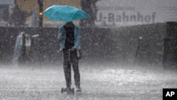 FILE - A girl with a scooter drives through a hailstorm in Munich, Germany, May 19, 2017.