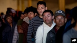 Honduran migrants stand in line for breakfast inside an empty warehouse that opened its doors to migrants in downtown Tijuana, Mexico, Dec. 18, 2018. Two teens from Honduras were killed in Tijuana while waiting to apply for asylum in the U.S.