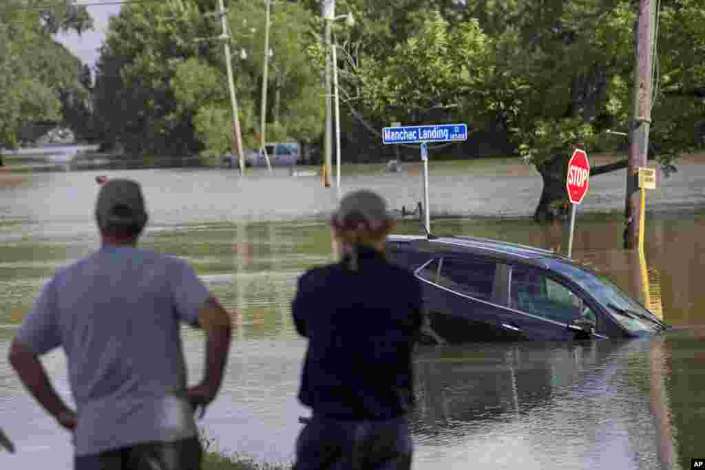 Residents survey the floodwater on Old Jefferson Highway at Bayou Manchac in Prairieville, La., Tuesday, Aug. 16, 2016.