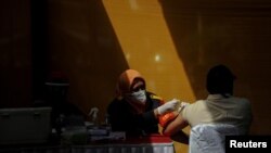 Un trabajador recibe una dosis contra el COVID-19 en una fábrica en Sumedang, Indonesia, el 5 de agosto de 2021. Existe una creciente preocupación por el impacto de una nueva oleada del virus en la economía mundial.