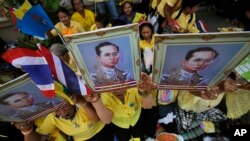 FILE - Supporters hold a portrait of Thai King Bhumibol Adulyadej in Bangkok, Thailand, May 10, 2015.