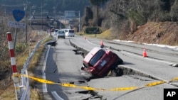 A car is trapped at a partially collapsed road caused by a powerful earthquake near Anamizu Town, Ishikawa Prefecture Tuesday, Jan. 2, 2024.