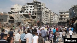 Residents arrive on foot to inspect their homes in the al-Hamdeya neighborhood, after the cessation of fighting between rebels and forces loyal to Syria's President Bashar al-Assad, in Homs city, Syria, May 9, 2014.
