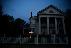 An illuminated cross stands in front of a residence near downtown Dawson, Ga., on April 17, 2020.