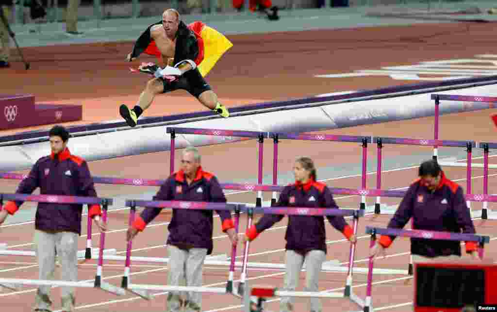Germany's Robert Harting celebrates winning the men's discus throw final by grabbing a German flag, running a lap of the track over the hurdles, and trying to wrench one of the burning torches from the Olympic cauldron.