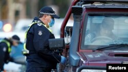 FILE - Police stop drivers at a checkpoint, set up in response to the state of Victoria's surge in coronavirus disease cases and resulting suburb lockdowns, in Melbourne, Australia, July 2, 2020.