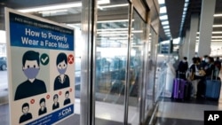 FILE - A sign stating face coverings are required is displayed at O'Hare airport in Chicago, July 2, 2021 The White House says it is considering requiring foreign visitors to show proof of vaccination.
