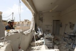 FILE - A member of the Syrian Civil Defense checks the rubble at a medical center following reported shelling by the Syrian government, in Hbeit in the southern countryside of the rebel-held Idlib province, April 30, 2019.