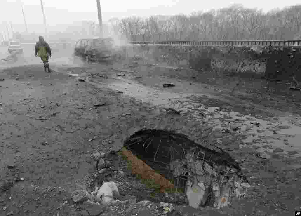 A pro-Russian rebel walks past a car destroyed by a rocket during recent shelling in Donetsk, Ukraine, Feb. 9, 2015.