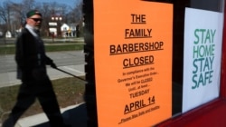 A pedestrian walks by The Family Barbershop, closed due to a Gov. Gretchen Whitmer executive order, in Grosse Pointe Woods, Mich., April 2, 2020.