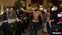 បុរស​ម្នាក់​ប៉ះទង្គិច​ជាមួយ​នឹង​ប៉ូលិស​នៅ​ខាង​ក្រៅ​ការិយាល័យ​ប៉ូលិស ក្នុង​ក្រុង Kenosha រដ្ឋ Wisconsin ក្នុង​អំឡុងពេល​តវ៉ា​ ក្រោយ​ពី​ប៉ូលិស​បាន​បាញ់​បុរស​ស្បែក​ខ្មៅ​ម្នាក់​ឈ្មោះ Jacob Blake កាល​ពី​ថ្ងៃ​ទី ២៣ ខែសីហា ឆ្នាំ​២០២០។ 