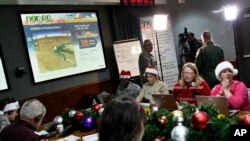 FILE - Volunteers take phone calls from children asking where Santa is and when he will deliver presents to their house, during the annual NORAD Tracks Santa Operation, at the North American Aerospace Defense Command, or NORAD, at Peterson Air Force Base, in Colorado Springs, Colorado, Dec. 24, 2012.