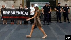 Serbian police officers guard members of the anti-war organization "Women in Black", holding a banner reading: " Srebrenica! We will never forget" as part of a protest in Belgrade, Serbia, July 6, 2015.