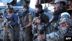 El personal de las fuerzas de seguridad afganas se encuentra junto a la carretera en Herat el 12 de agosto de 2021, mientras los combatientes talibanes tomaron el cuartel general de la policía en Herat.