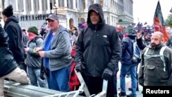 Un hombre (centro con abrigo negro) identificado por los fiscales federales de Estado Unidos como Shane Jason Woods de Auburn, Illinois. Captura de fotograma de un video filmado durante el asalto del 6 de enero de 2021 al Capitolio.