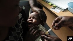 A mother holds her baby as she receives a new malaria vaccine at the Walter Reed Project Research Center in Kenya, October 30, 2009. 