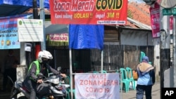 Seorang pengendara sepeda motor melewati sebuah kampung di Jakarta, yang diisolasi setelah beberapa warganya terpapar virus corona COVID-19, 22 Juni 2021. (Foto: BAY ISMOYO / AFP). 
