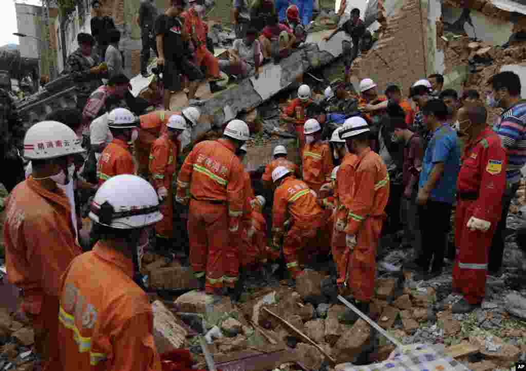 Rescuers try to retrieve a trapped victim's body from a collapsed house following a massive earthquake in the town of Longtoushan in Ludian County in southwest China's Yunnan Province, Aug. 5, 2014.