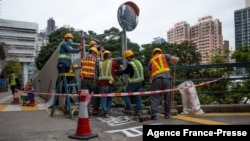 Construction workers at the University of Hong Kong use metal sheeting to cover up one of the city's last public tributes to the deadly 1989 Tiananmen Square crackdown, Jan. 29, 2022.