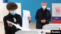 A woman casts her ballots at a polling station on the last day of three-day long parliamentary elections in Moscow, Russia, Sept. 19, 2021. 