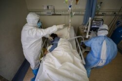 Medical workers in protective suits attend to a patient inside an isolated ward of Wuhan Red Cross Hospital in Wuhan, the epicenter of the novel coronavirus outbreak, in Hubei province, China, Feb. 16, 2020. (Credit: China Daily)