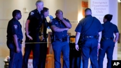 A Dallas police officer covers his face as he stands with others outside the emergency room at Baylor University Medical Center, July 8, 2016, in Dallas. 