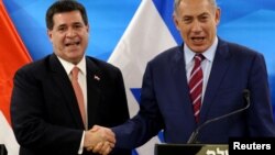 El primer ministro israelí, Benjamin Netanyahu (derecha) estrecha la mano del presidente de Paraguay, Horacio Cartes, en Jerusalén el lunes, 21 de mayo, de 2018.