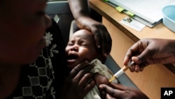 FILE - A mother holds her baby receiving a new malaria vaccine as part of a trial at the Walter Reed Project Research Center in Kombewa in Western Kenya on Oct. 30, 2009. Cameroon is beginning the world's first routine immunization program against malaria for children.