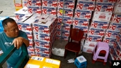 A man waits for the goods to be load on his tricycle at a dealer selling imported seafoods at the Jingshen seafood market in Beijing, Thursday, July 12, 2018. 