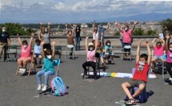 Parents and children take part in a flashmob entitled "Open School" at the Gianicolo Belvedere overlooking Rome on June 8, 2020, to mark the end of their "unusual school year" as the country eases its lockdown.