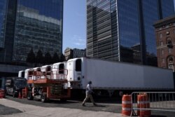 A worker walks past freezer trucks to store cadavers, part of a makeshift morgue behind a hospital, during the outbreak of coronavirus disease, in the Manhattan borough of New York City, New York, March 26, 2020.