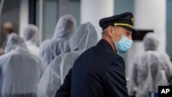 FILE - In this April 18, 2020 file photo, a pilot and crew members of South African Airways. Questions are swirling in Africa over the financial wisdom of sustaining prestige carriers amid coronavirus-related travel restrictions.