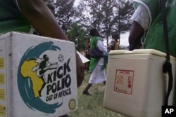 FILE - Polio vaccination field officials walk with their vaccine carrier on their way to make house-to-house visits to immunize children in Lagos, Nigeria, Oct. 24, 2003.
