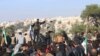 FILE - In this frame grab from video taken on Dec. 20, 2019, Hayat Tahrir al-Sham militants try to disperse people gathered at the Bab al-Hawa border gate to protest the ongoing bombing campaign in Syria's rebel-controlled Idlib province.