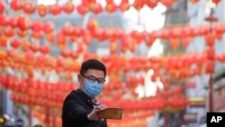 A man wears a mask as he takes a photograph in China Town in London, Feb. 7, 2020. 