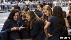 A group of Catholic school girls look at their phones as they wait on the route that Pope Francis will take later in the day near St. Patrick’s Cathedral in New York Sept. 24, 2015.