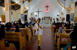 A boy holds a processional cross during Mass at St. Joseph's church in Thannamunai, Sri Lanka, April 30, 2019.
